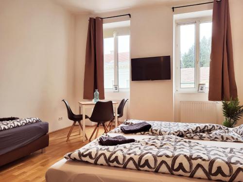 a bedroom with two beds and a desk with chairs at Floridsdorfer Apartment - Free Highspeed-Internet in Vienna