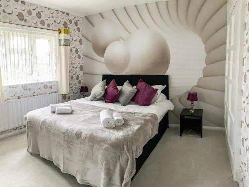 a bedroom with a large bed with purple pillows at Briar Cottage in Knaresborough