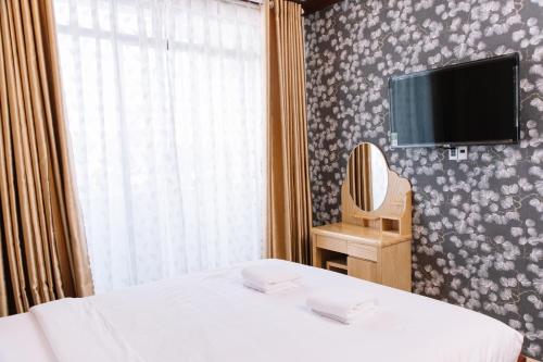 a bedroom with a bed and a tv on a wall at Hoa Hướng Dương Hotel in Phan Rang