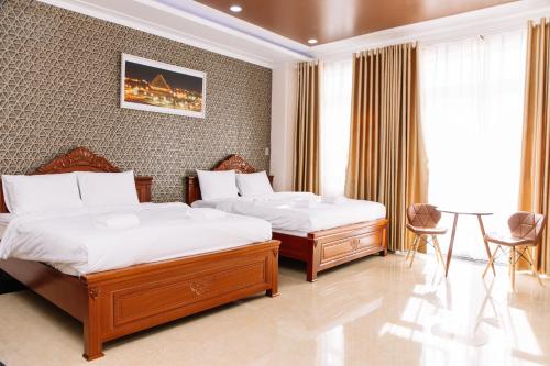 a hotel room with two beds and a table and chairs at Hoa Hướng Dương Hotel in Phan Rang