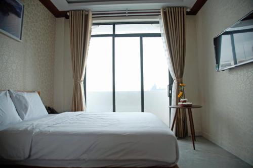 a bedroom with a bed and a large window at Hoa Hướng Dương Hotel in Phan Rang