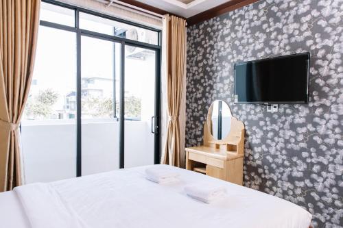 a bedroom with a bed and a tv on a wall at Hoa Hướng Dương Hotel in Phan Rang