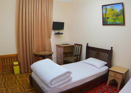 a small bedroom with a bed and a desk at Madina-Mehribon in Bukhara