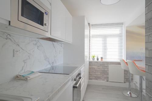 una cocina con encimeras de mármol blanco y una ventana en Sea View Kemptown Holiday Let, en Brighton & Hove
