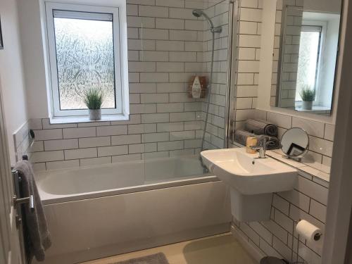 a bathroom with a sink and a bath tub and a sink at Clock Tower Cottage in Whitchurch