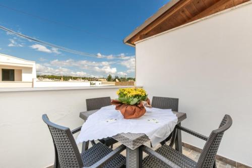 una mesa con sillas y un jarrón de flores en el balcón en Lido Marini Apartments - Happy Rentals, en Salve