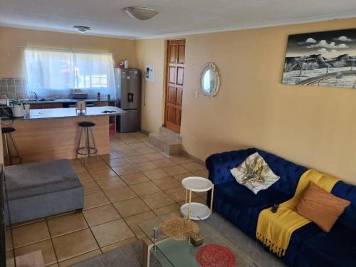 a living room with a blue couch and a kitchen at Self catering unit in Johannesburg