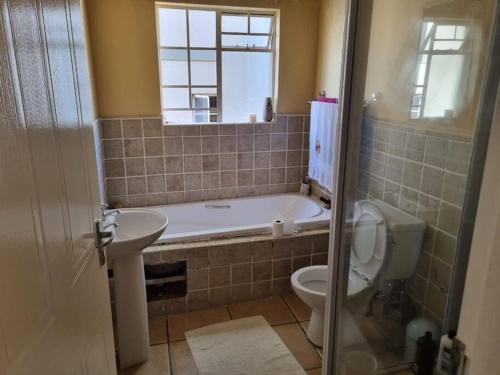 a bathroom with a tub and a toilet and a sink at Self catering unit in Johannesburg