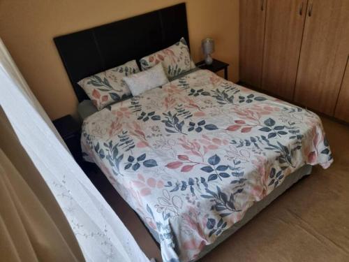 a bedroom with a bed with a floral bedspread at Self catering unit in Johannesburg
