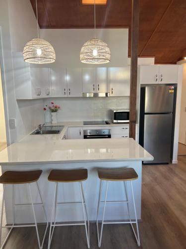 a kitchen with a large white island with two bar stools at Marlin Villa - Hervey Bay in Urangan