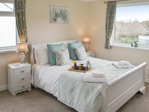 a bedroom with a white bed and two windows at Thistle Dee in Wooler