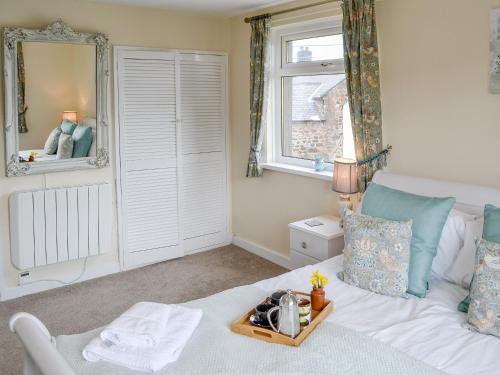 a bedroom with a white bed with a tray on it at Thistle Dee in Wooler