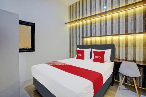 ein Schlafzimmer mit einem Bett mit zwei roten Kissen in der Unterkunft OYO 92435 Sunlo Cozy Home Family Homestay Syariah in Surabaya