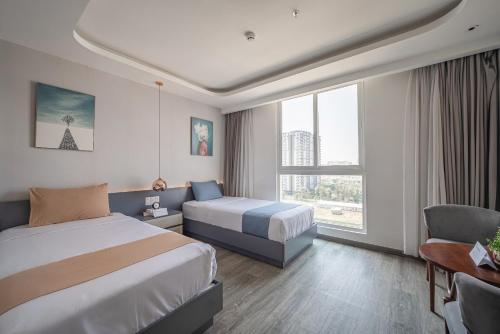 a hotel room with two beds and a chair at Cozrum Homes - Sonata Residence in Ho Chi Minh City