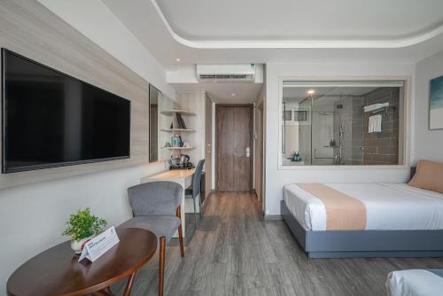 a hotel room with a bed and a desk and a television at Cozrum Homes - Sonata Residence in Ho Chi Minh City