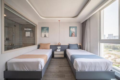 two beds in a room with a window at Cozrum Homes - Sonata Residence in Ho Chi Minh City