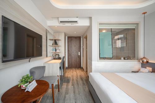 a hotel room with a bed and a table and a television at Cozrum Homes - Sonata Residence in Ho Chi Minh City
