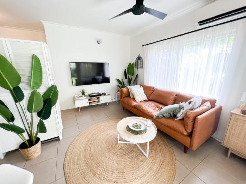 a living room with a brown couch and a table at Unit 18 @ Marina Terraces Port Douglas in Port Douglas
