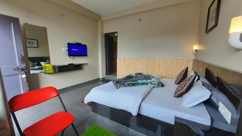 - une chambre avec un lit et une chaise rouge dans l'établissement FORTUNE HEIGHTS DALHOUSiE, à Dalhousie