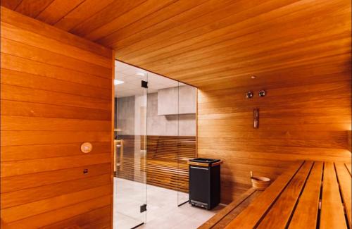 克拉科夫的住宿－CozyStudio with Sauna，一间设有木镶板和玻璃墙的桑拿浴室