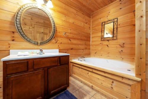 ein Badezimmer mit einer Badewanne, einem Waschbecken und einem Spiegel in der Unterkunft Parkview Vista Way Home 1353 in Pigeon Forge