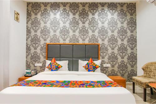 a bedroom with a large bed and a chair at FabHotel Prime Royal Maple in Ludhiana