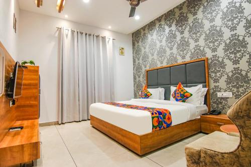 a bedroom with a large bed and a chair at FabHotel Prime Royal Maple in Ludhiana