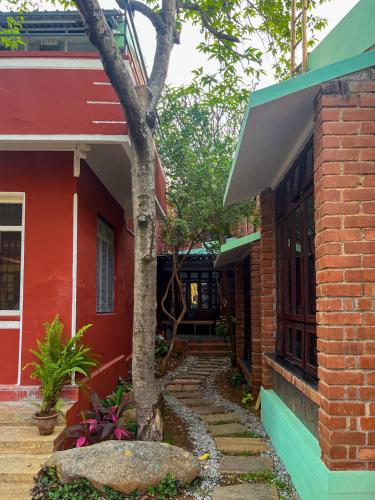a red house with a tree in front of it at Rahees Bi Roambay - Backpacker Hostel in Mysore