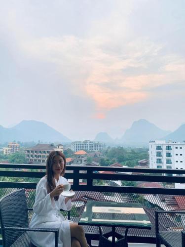 a woman sitting on a balcony with a plate of food at VANG VIENG TOPVIEW HOTEL in Vang Vieng