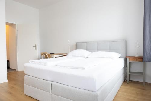 Cette chambre comprend un grand lit blanc et une table. dans l'établissement DS Apartment 5, à Vienne