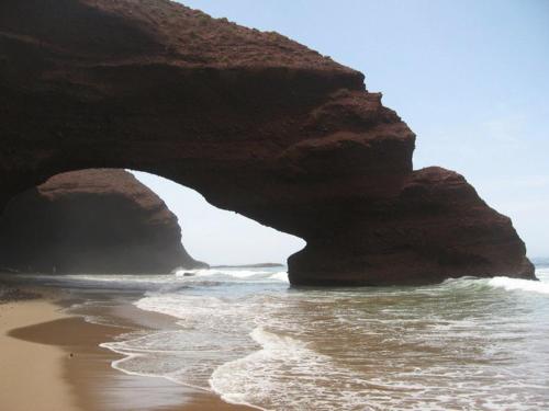 a beach with a large rock bridge over the water at Mirleft Trip in Mirleft