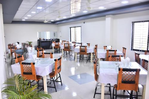 une salle à manger avec des tables et des chaises blanches dans l'établissement Hotel River View, à Sylhet