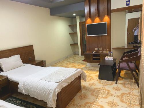 a bedroom with a bed and a desk and a television at Hotel River View in Sylhet