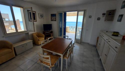 una cucina con tavolo e una sala da pranzo con vista sull'oceano di 058 Spiaggia di SalentoInVacanza.Com a Torre Pali
