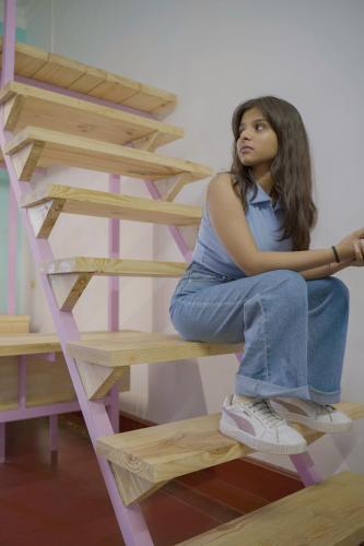a young woman sitting on a wooden stairs at Rahees Bi Roambay - Backpacker Hostel in Mysore