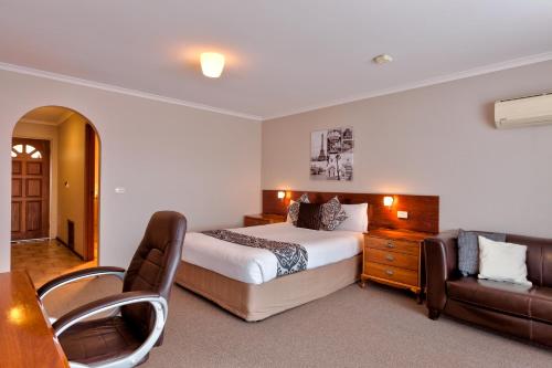 a bedroom with a bed and a desk and a couch at Hume Country Motor Inn in Albury