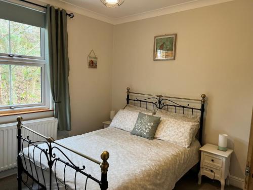 a bedroom with a bed and a window at Cosy Heather Cottage in Ashbourne