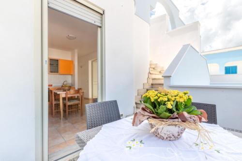 una mesa con un jarrón de flores amarillas. en Lido Marini Apartments - Happy Rentals, en Salve