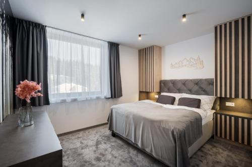 a bedroom with a large bed and a vase of flowers at Chalet Pod Brdom - Apartments in Ružomberok