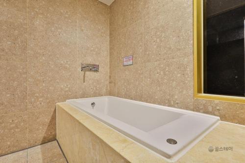 uma banheira branca na casa de banho com uma janela em Gracias Hotel Gimhae em Gimhae