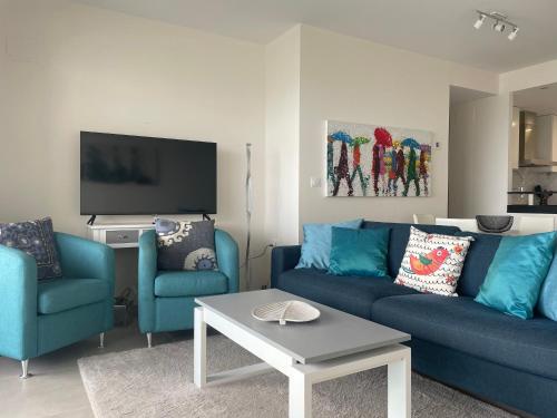 a living room with two blue couches and a tv at Apartamento en Sea Senses Freya in Torrevieja