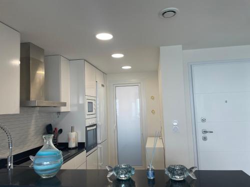 a white kitchen with a blue vase on a counter at Apartamento en Sea Senses Freya in Torrevieja
