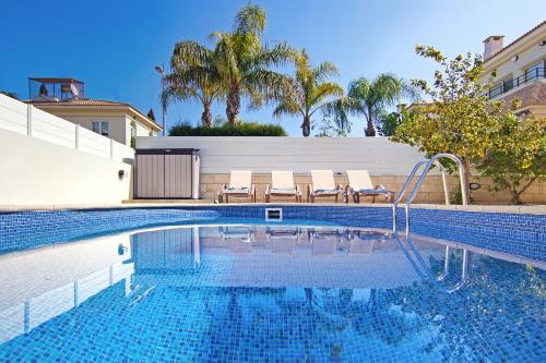 een zwembad met stoelen en palmbomen op de achtergrond bij Villa Sonja in Protaras