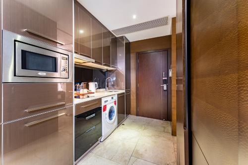 a kitchen with a refrigerator and a washer and dryer at QingMan Apartment Guangzhou Zhujiang New Town East Railway Station Branch in Guangzhou