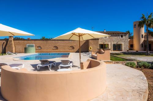 a swimming pool with two chairs and an umbrella at Casa Fina in Felanitx