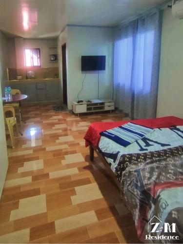a bedroom with a bed and a television on a wooden floor at ZM Residence in Dapa