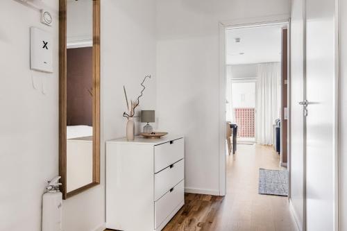 a white bedroom with a mirror and a dresser at Studio Living in Karlskrona