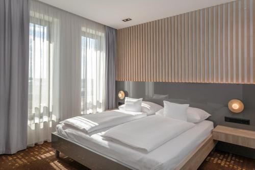 a bedroom with a large white bed and windows at Flow Hotel & Conference in Inárcs