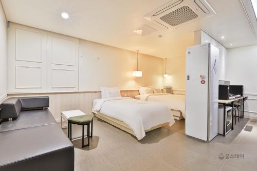 um quarto de hotel com duas camas e um frigorífico em Gracias Hotel Gimhae em Gimhae