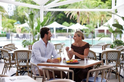 Un uomo e una donna seduti a un tavolo in un ristorante di RACV Royal Pines Resort Gold Coast a Gold Coast